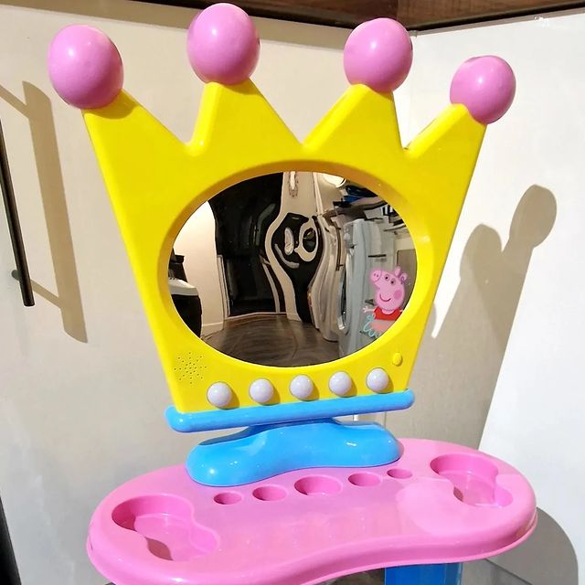 A colorful Peppa Pig dressing table with a crown-shaped mirror and compartments for accessories.
