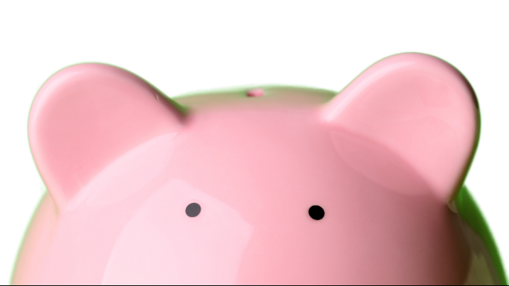 Close-up of a pink piggy bank with cartoon-like ears and facial features.